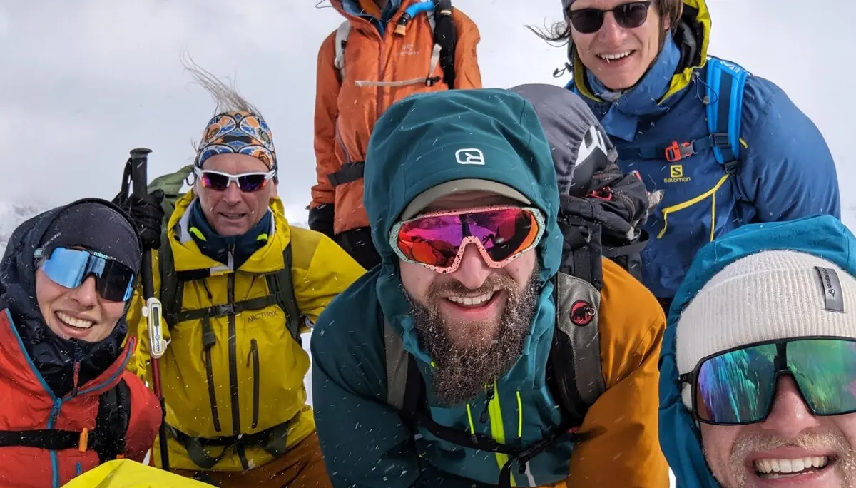 Sieben Personen machen ein Selfie bei windigem Wetter auf dem verschneiten Gipfel. | © DAV Dortmund