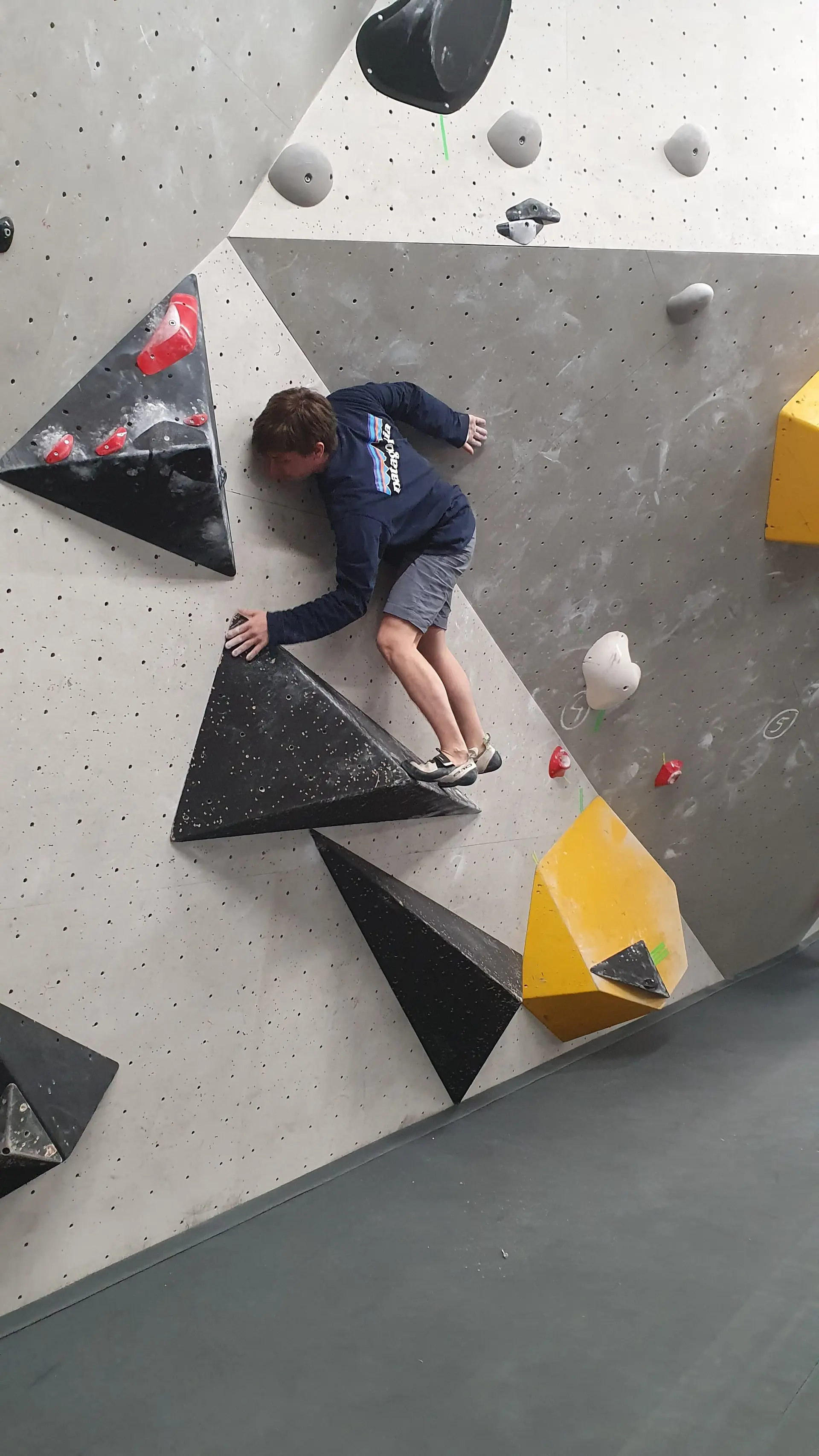 Ein Jugendlicher klettert an einer schwarz-gelben Boulderroute in der Halle. | © DAV Dortmund