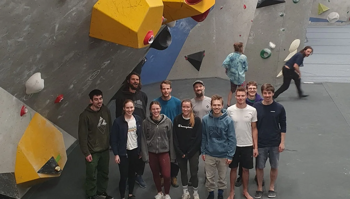 Eine Gruppe von Jugendlichen steht vor einer Boulderwand mit gelben Griffen in einer Halle. | © DAV Dortmund