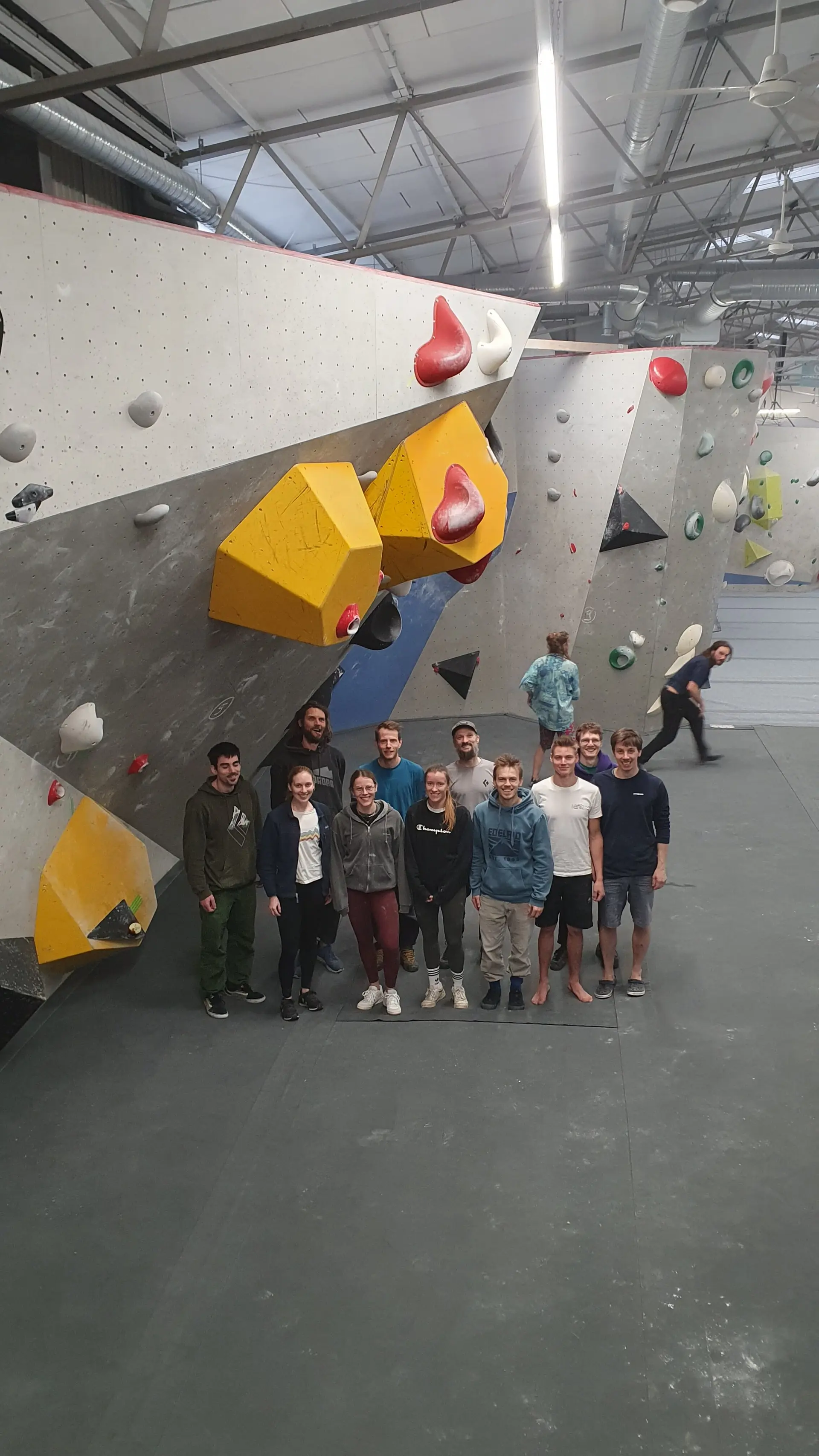 Eine Gruppe von Jugendlichen steht vor einer Boulderwand mit gelben Griffen in einer Halle. | © DAV Dortmund