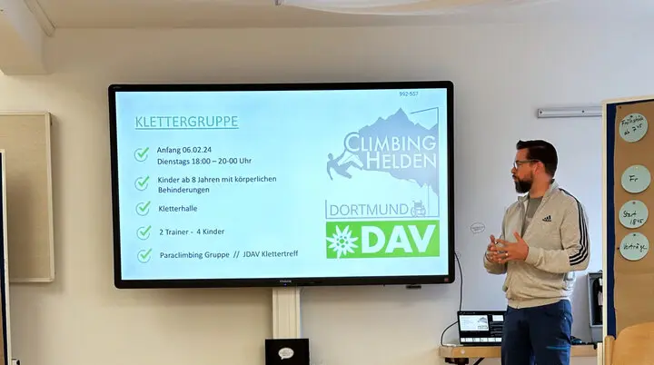 Ein Mann steht vor einer Leinwand mit Präsentation über Sektionsaktivitäten im DAV Dortmund. | © DAV Dortmund