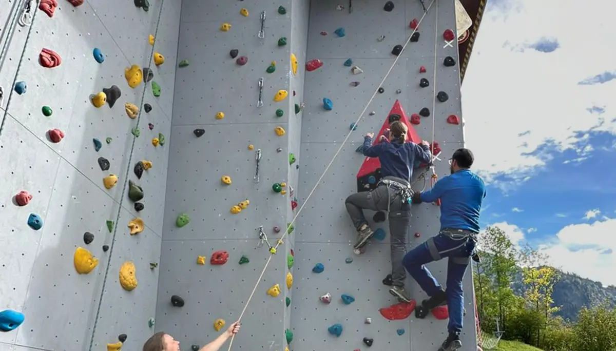 Zwei Personen klettern an einer künstlichen Außenwand, eine dritte Person sichert mit Seil. | © DAV Dortmund