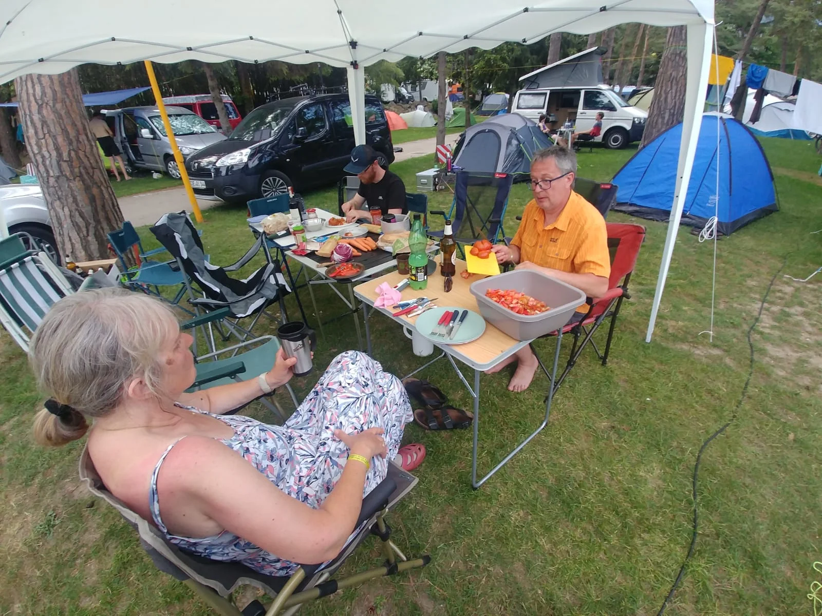 Zwei Personen sitzen unter einem Pavillon an einem gedeckten Campingtisch auf einem Zeltplatz. | © DAV Dortmund