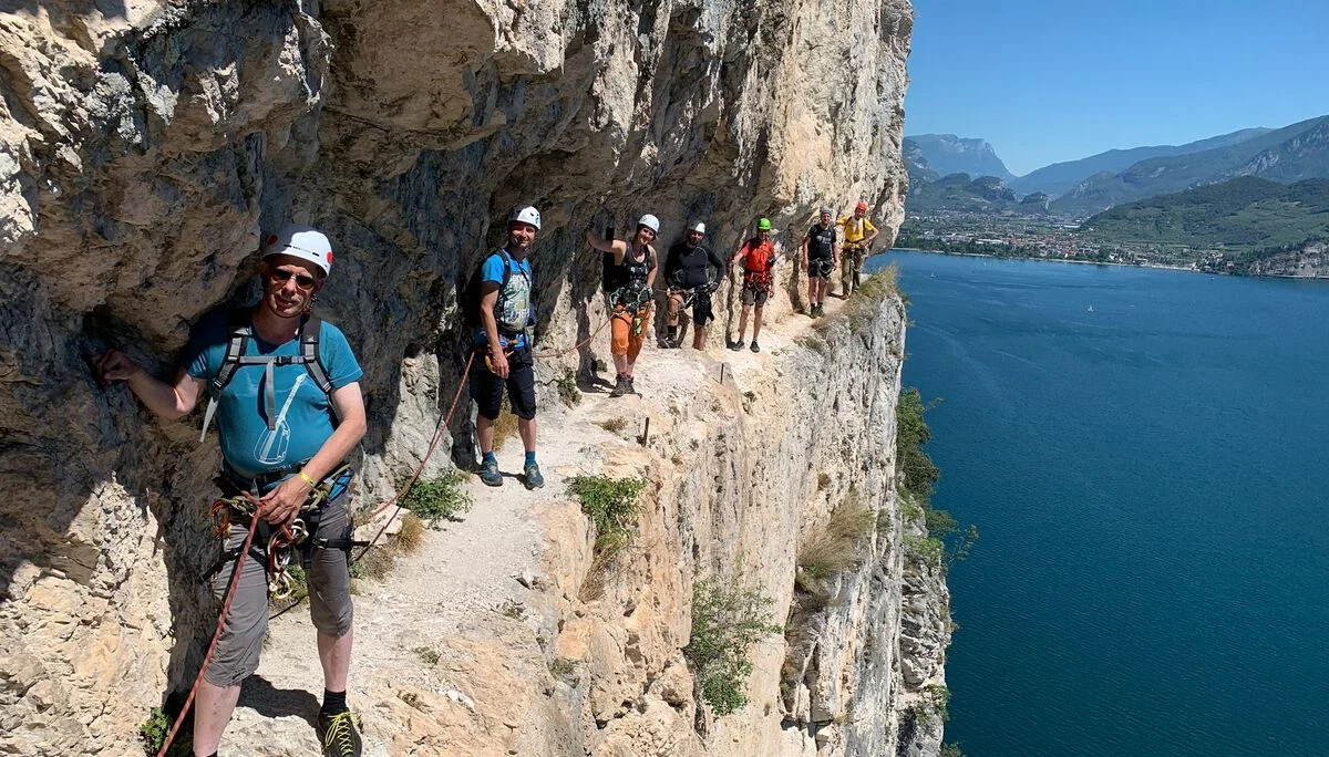 Gruppe auf einem gesicherten Steig an einer steilen Felswand mit Blick auf den Gardasee. | © DAV Dortmund