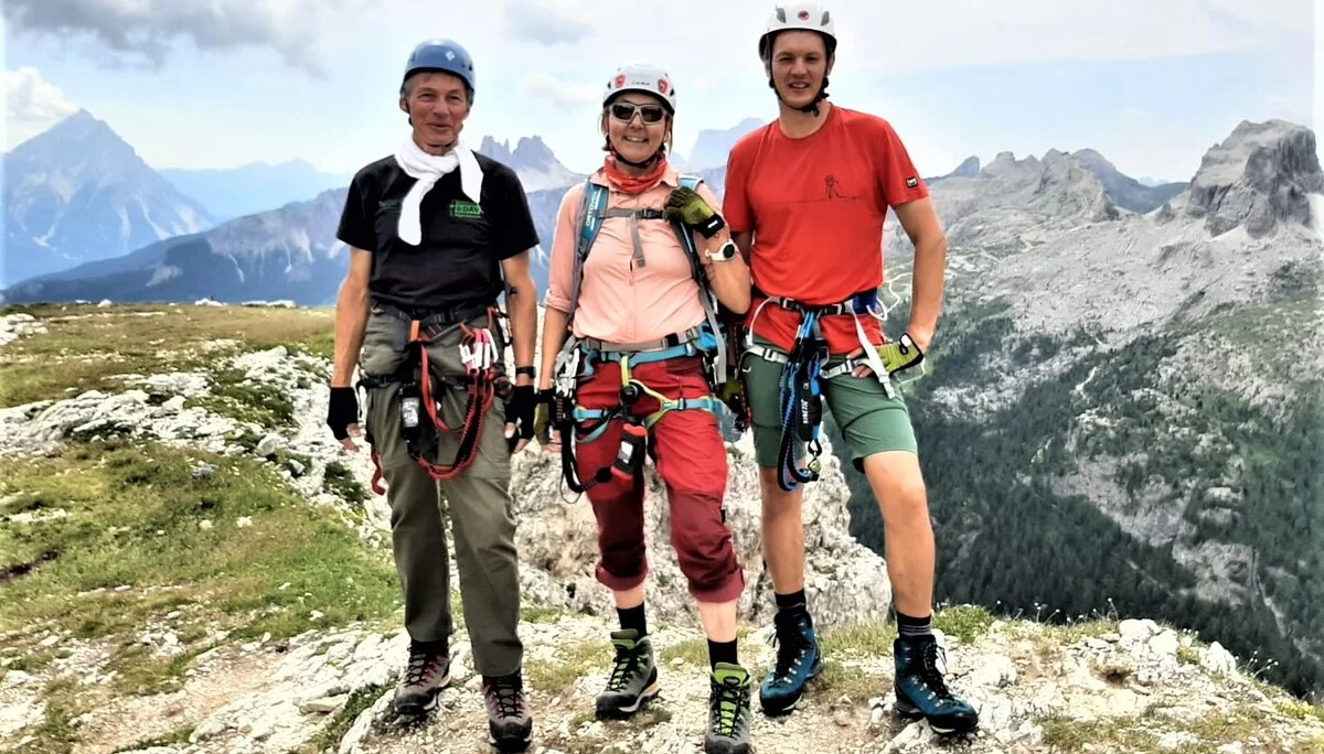 Drei Personen mit Kletterausrüstung stehen auf einem Gipfelplateau mit Blick auf umliegende Berge. | © DAV Dortmund