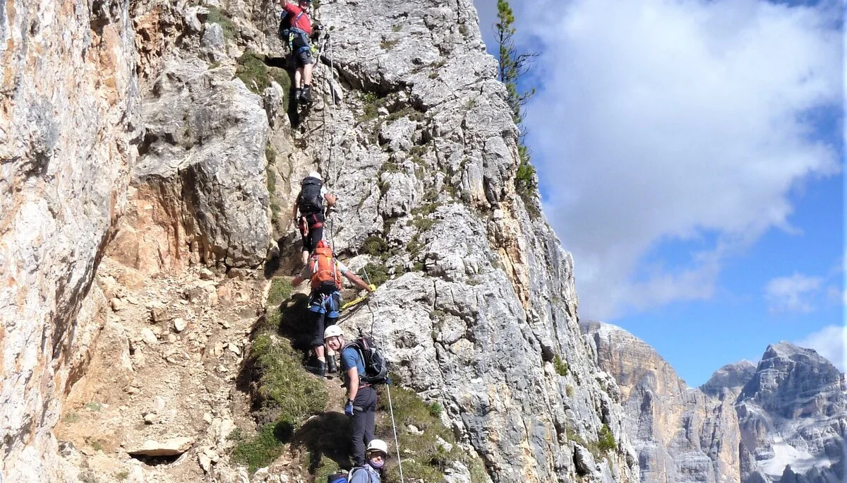 Eine Gruppe von Personen klettert über einen schmalen Felssteig in den Bergen. | © DAV Dortmund