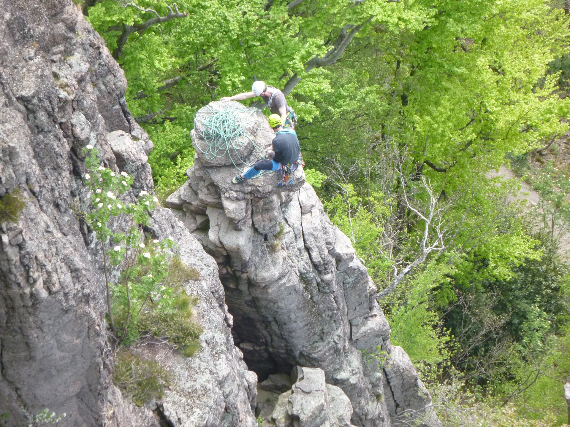 Zwei Personen stehen mit Seil und Ausrüstung auf einem Felsvorsprung im Waldgebiet. | © DAV Dortmund