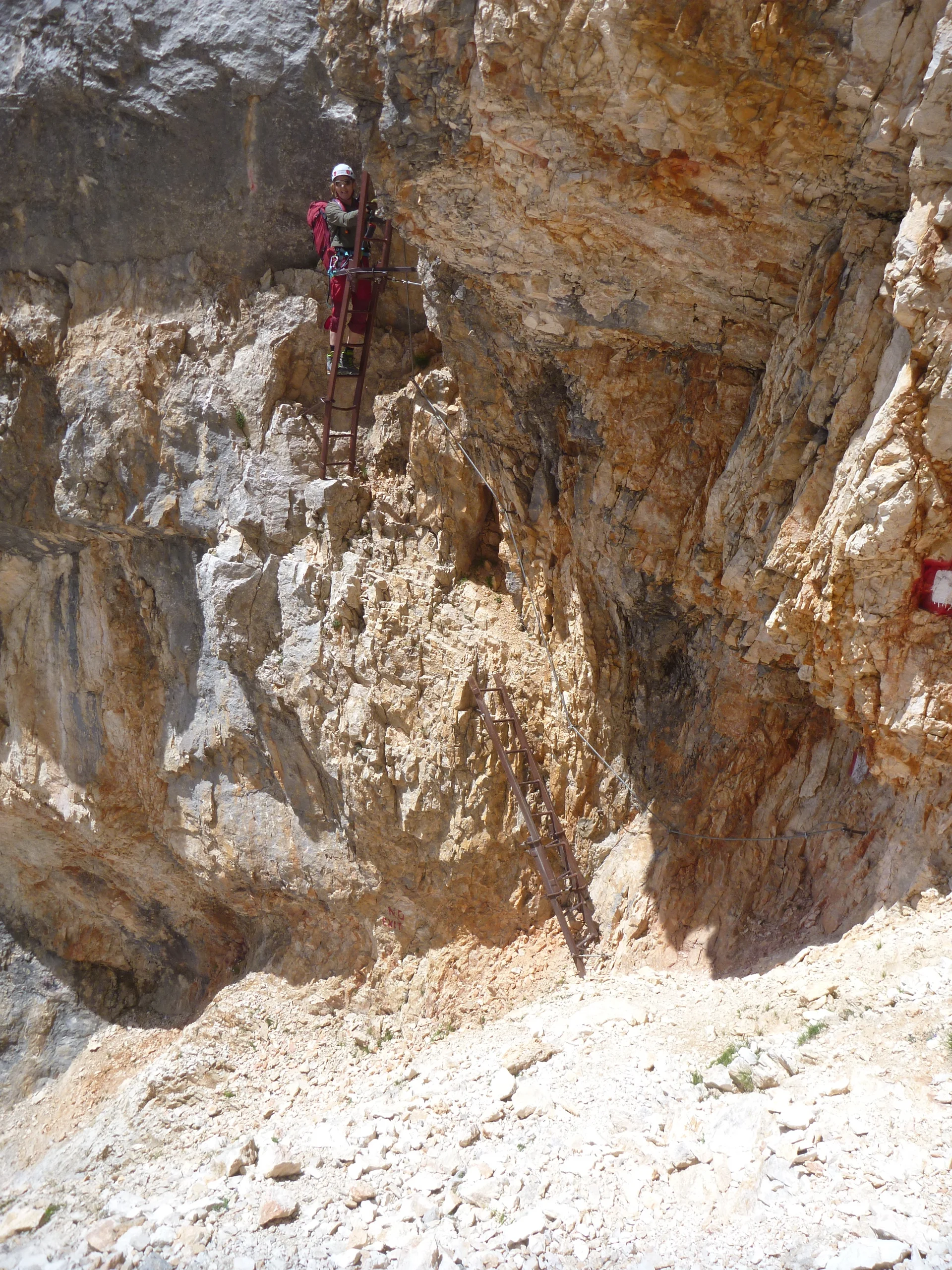 Zwei Personen steigen eine senkrechte Metallleiter in einer rötlichen Felswand hinauf. | © DAV Dortmund