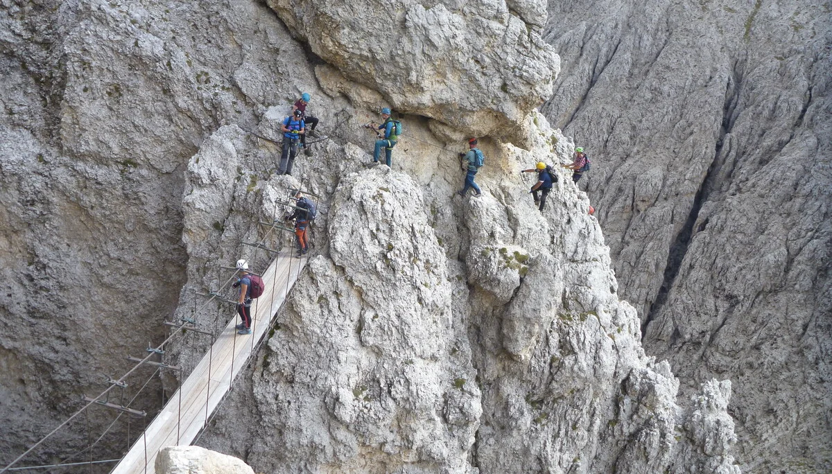 Eine Gruppe Bergsteiger*innen überquert eine Hängebrücke in einem steilen Klettersteigabschnitt. | © DAV Dortmund