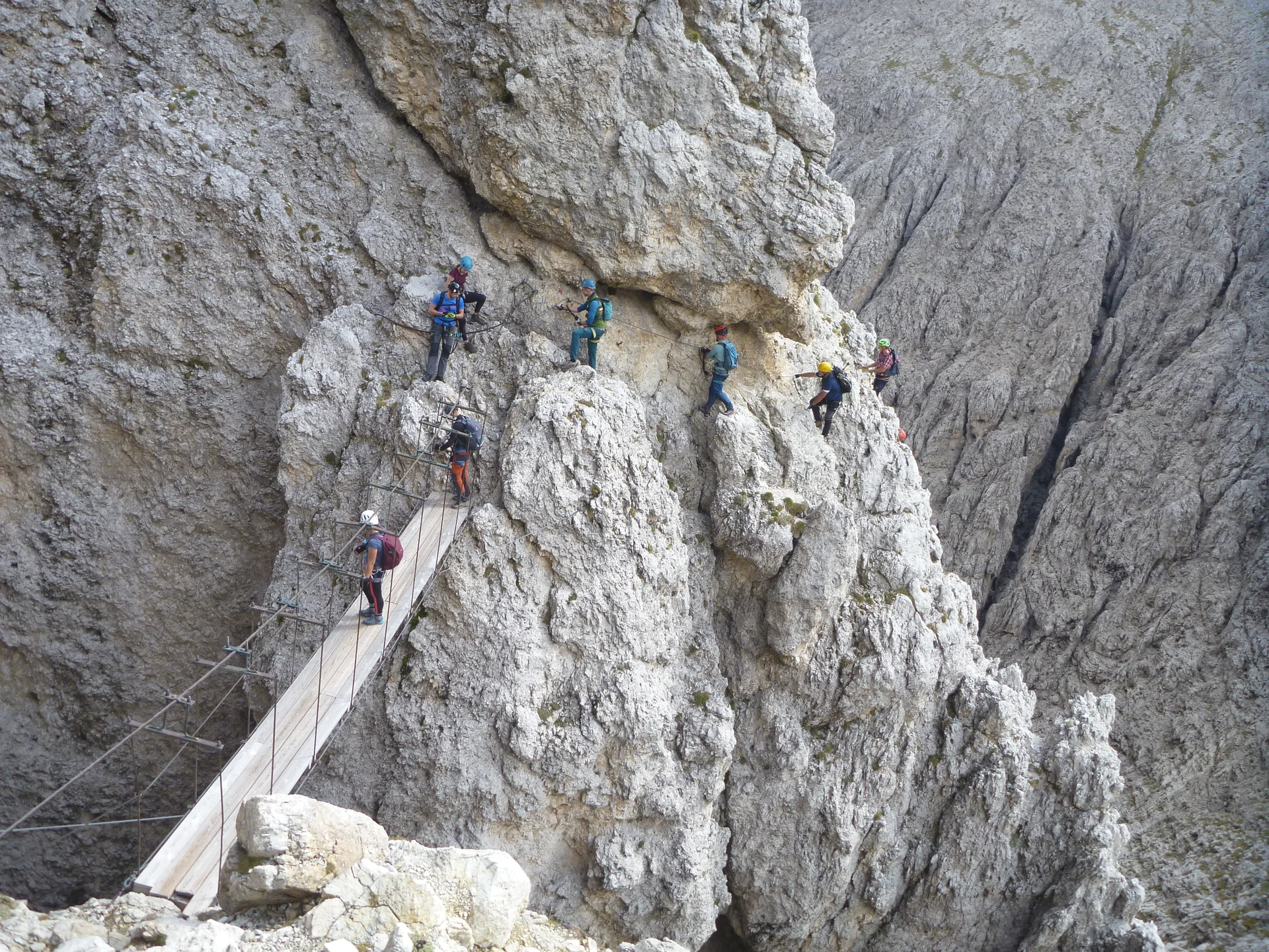 Eine Gruppe Bergsteiger*innen überquert eine Hängebrücke in einem steilen Klettersteigabschnitt. | © DAV Dortmund