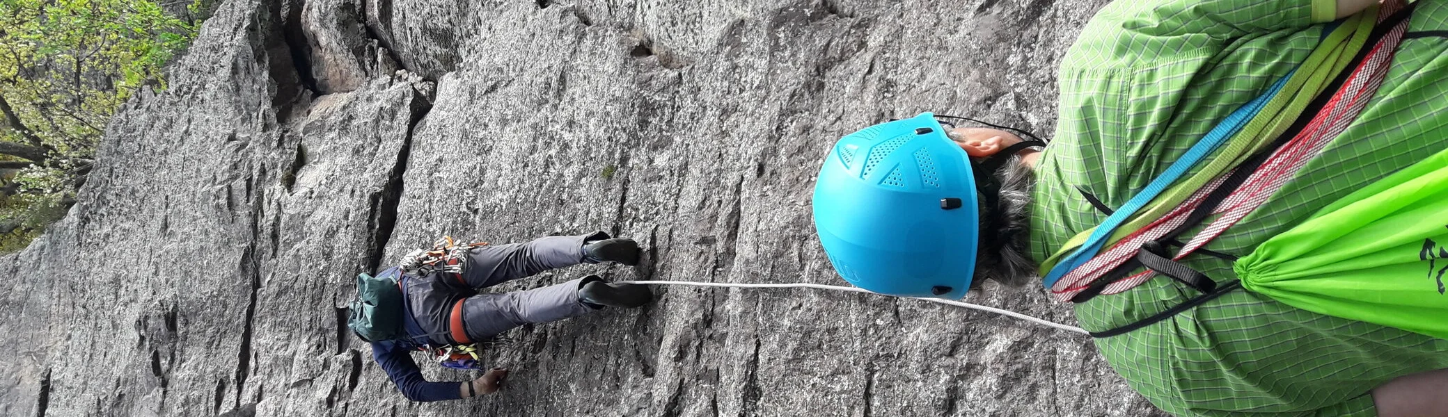 Eine Person klettert an einem steilen Fels, gesichert von einer zweiten Person mit Helm am Boden. | © DAV Dortmund