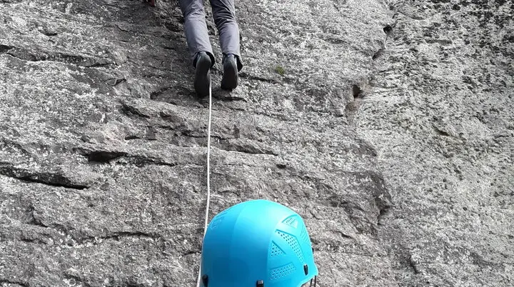 Eine Person klettert an einem steilen Fels, gesichert von einer zweiten Person mit Helm am Boden. | © DAV Dortmund