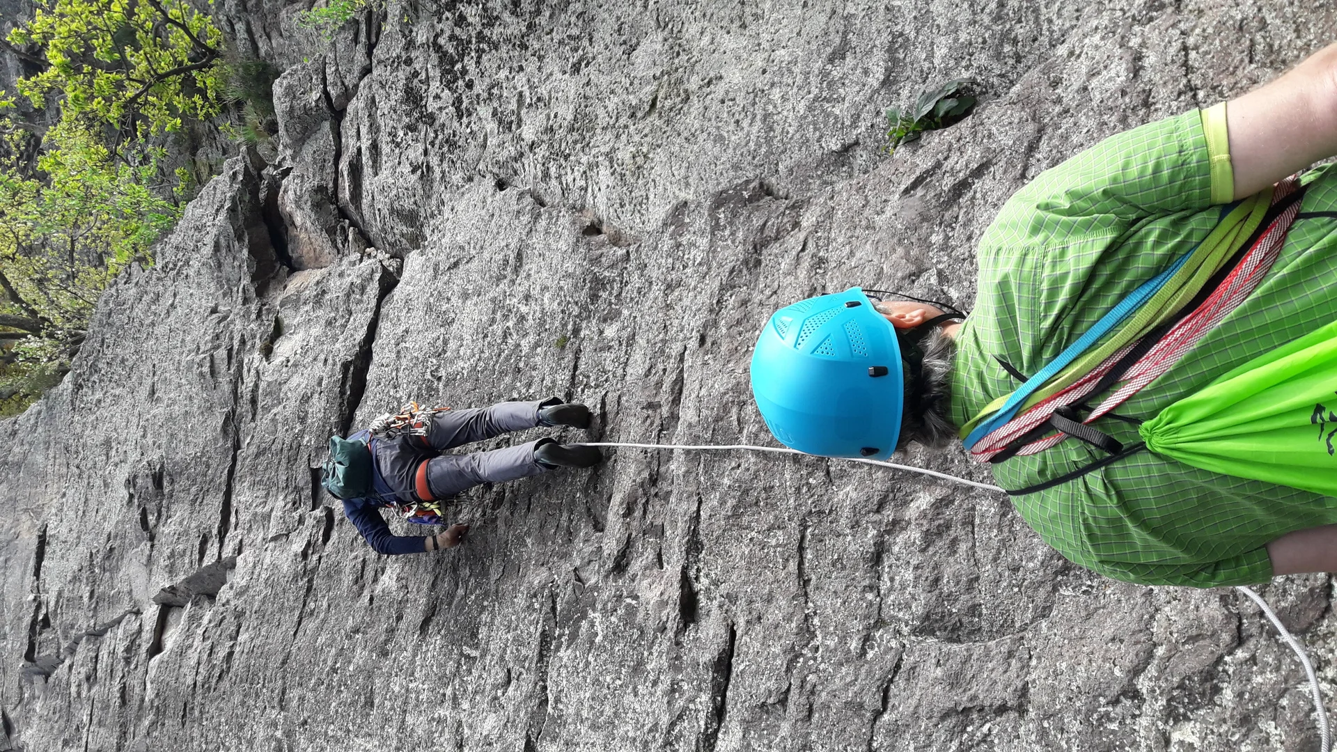 Eine Person klettert an einem steilen Fels, gesichert von einer zweiten Person mit Helm am Boden. | © DAV Dortmund