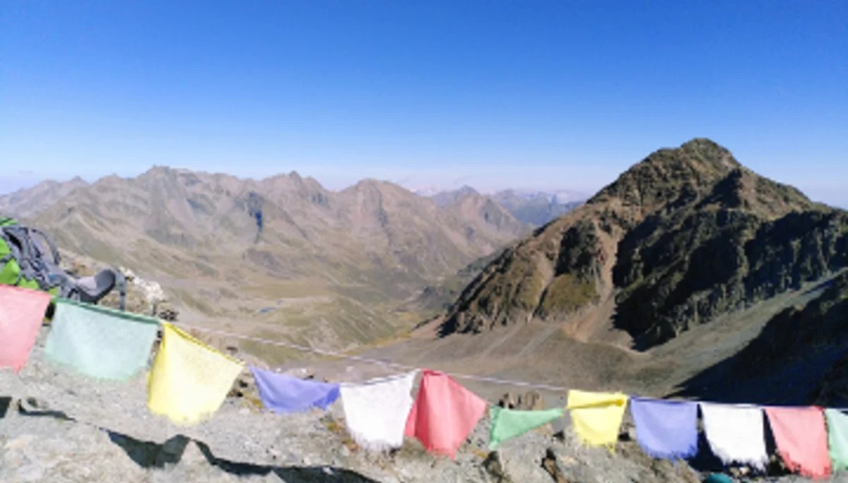 Bunte tibetische Gebetsfahnen flattern vor weiter Berglandschaft unter wolkenlosem Himmel. | © DAV Dortmund