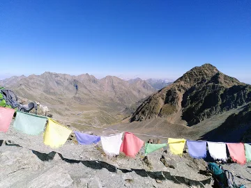 Bunte tibetische Gebetsfahnen flattern vor weiter Berglandschaft unter wolkenlosem Himmel. | © DAV Dortmund