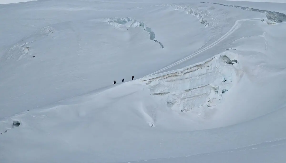 Drei Bergsteiger*innen bewegen sich gesichert in einer Seilschaft über einen schneebedeckten Gletscher, umgeben von großen Gletscherspalten und Felsformationen. | © DAV Dortmund
