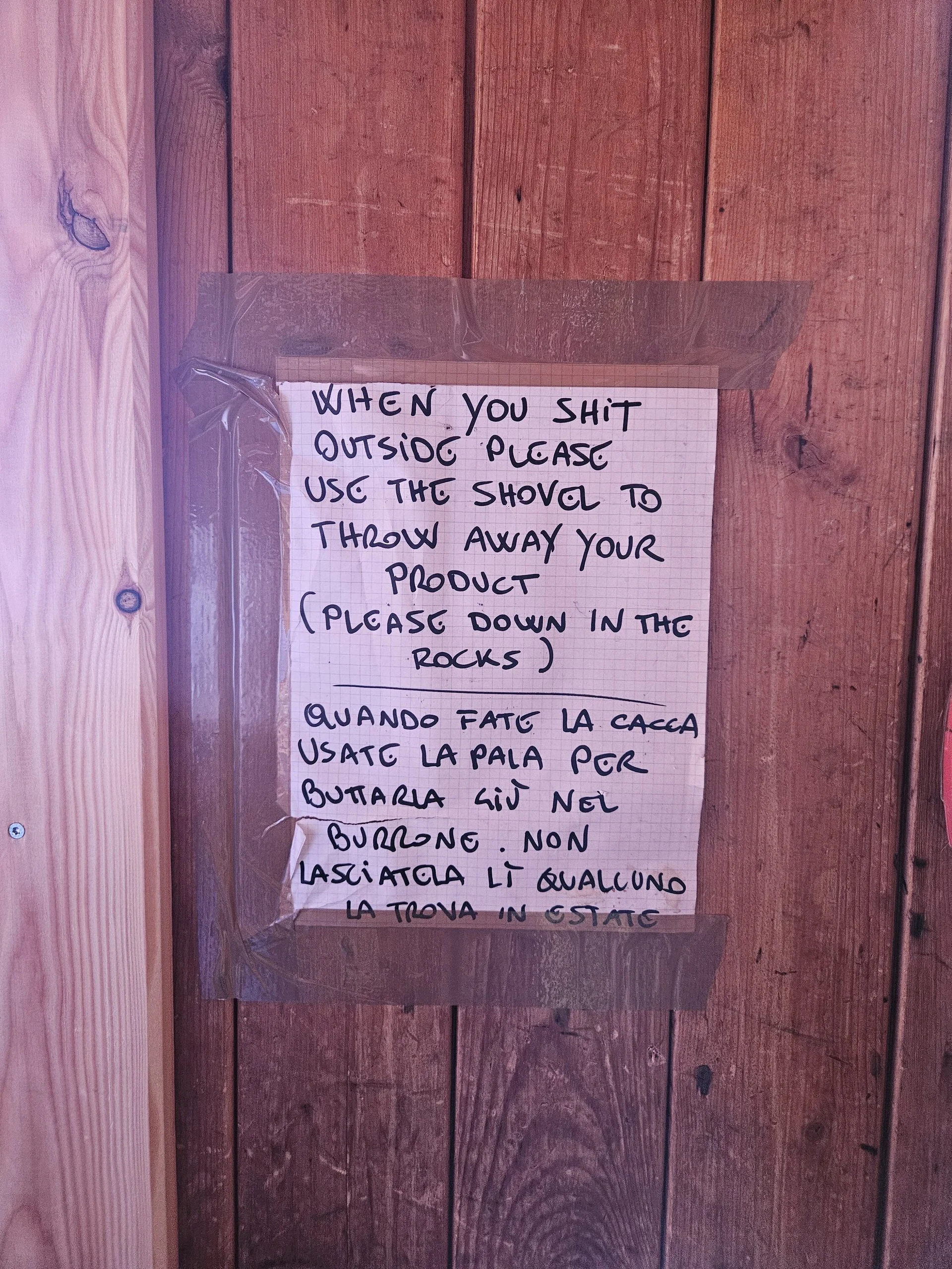 Handgeschriebener Zettel an einer Holzwand, der Besucher auffordert, beim Toilettengang draußen eine Schaufel zu benutzen und die Hinterlassenschaft in den Felsen zu entsorgen. Text auf Englisch und Italienisch. | © DAV Dortmund