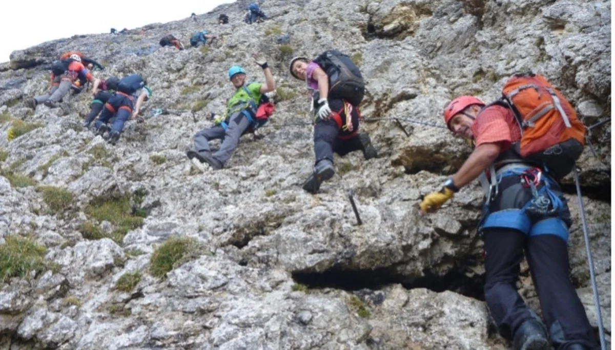 Eine größere Gruppe bewegt sich mit Kletterausrüstung schräg über eine steile Felswand. | © DAV Dortmund