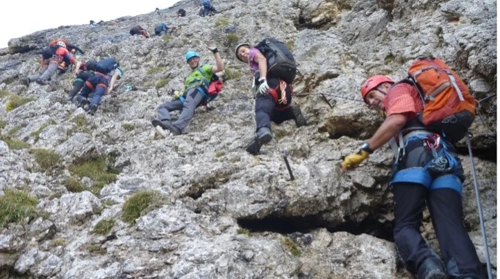Eine größere Gruppe bewegt sich mit Kletterausrüstung schräg über eine steile Felswand. | © DAV Dortmund