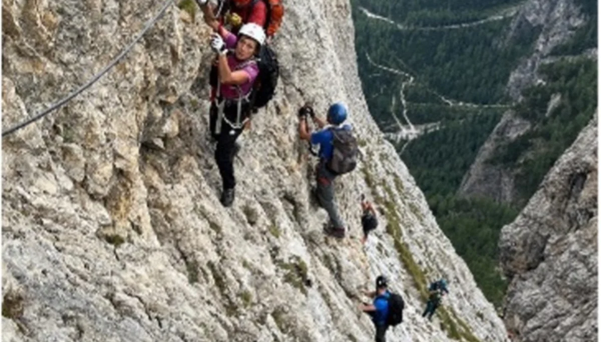 Mehrere Personen mit Helm und Gurt klettern gesichert an einem steilen Klettersteig mit Blick ins Tal. | © DAV Dortmund