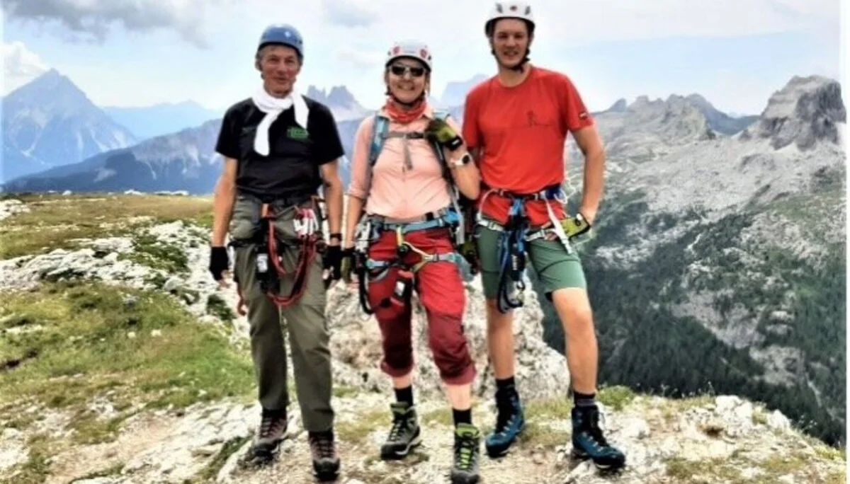 Drei Personen in Kletterausrüstung stehen nebeneinander auf einem Berg mit Ausblick auf die Dolomiten. | © DAV Dortmund