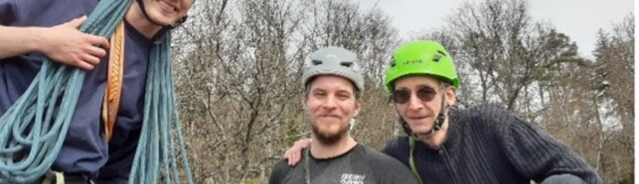 Drei Männer mit Kletterausrüstung und Helmen lächeln in die Kamera beim Felsklettern. | © DAV Dortmund