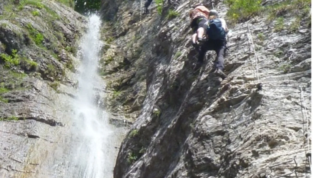  Zwei Kletternde bewegen sich auf einem Klettersteig neben einem schmalen Wasserfall. | © DAV Dortmund