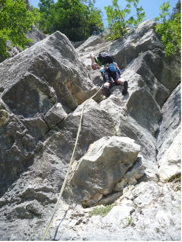 Eine Person seilt sich an einer steilen, zerklüfteten Felswand mit Sicherung ab. | © DAV Dortmund