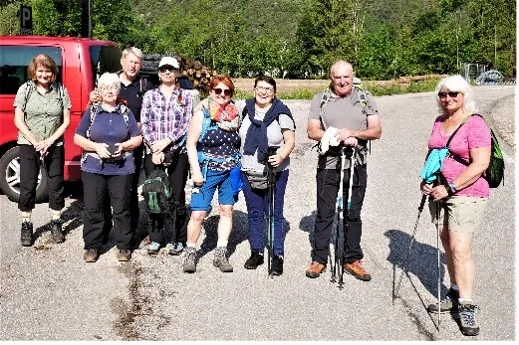 Eine Gruppe älterer Wander*innen steht mit Wanderstöcken und Rucksäcken auf einem Parkplatz, bereit für eine Tour. | © DAV Dortmund