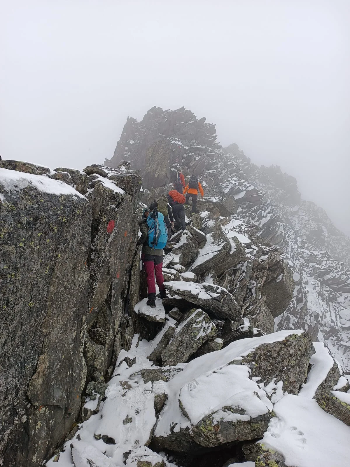 Mehrere Personen steigen über einen schmalen, verschneiten Felsgrat bei Nebel und Kälte. | © DAV Dortmund