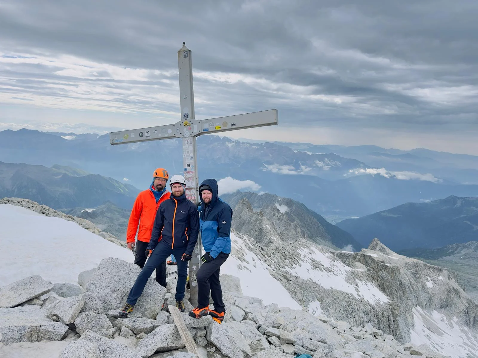 Vier Bergsteiger stehen neben einem Gipfelkreuz auf felsigem Terrain mit Aussicht auf ein Gebirge. | © DAV Dortmund