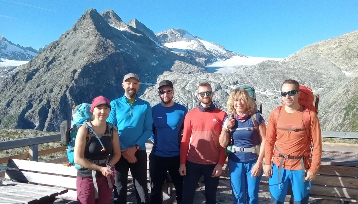 Sechs Personen posieren auf einer Terrasse vor einem Gletscher und hohen Bergen bei Sonnenschein | © DAV Dortmund