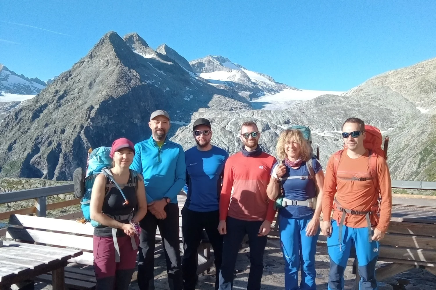 Sechs Personen posieren auf einer Terrasse vor einem Gletscher und hohen Bergen bei Sonnenschein | © DAV Dortmund