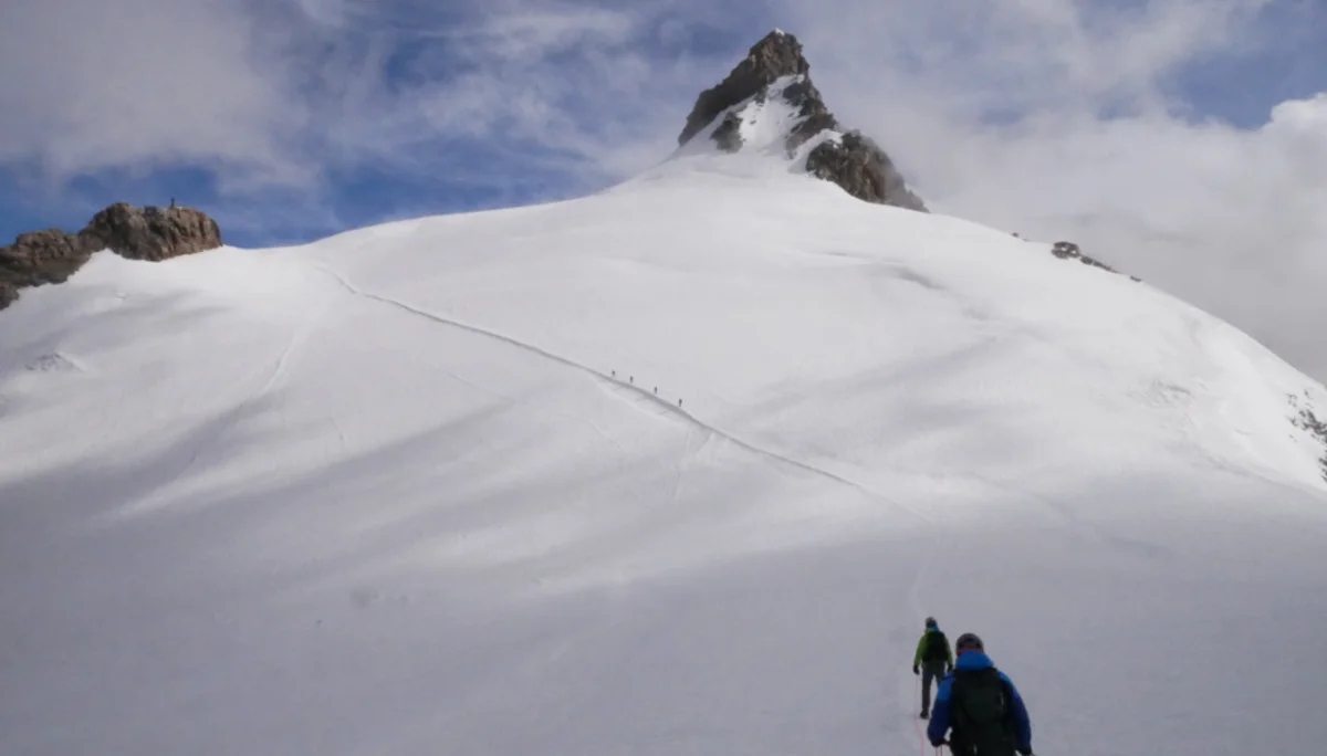 Zwei Bergsteiger*innen gehen über ein verschneites Gletscherfeld auf einen Gipfel zu. | © DAv Dortmund