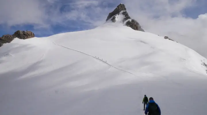 Zwei Bergsteiger*innen gehen über ein verschneites Gletscherfeld auf einen Gipfel zu. | © DAv Dortmund