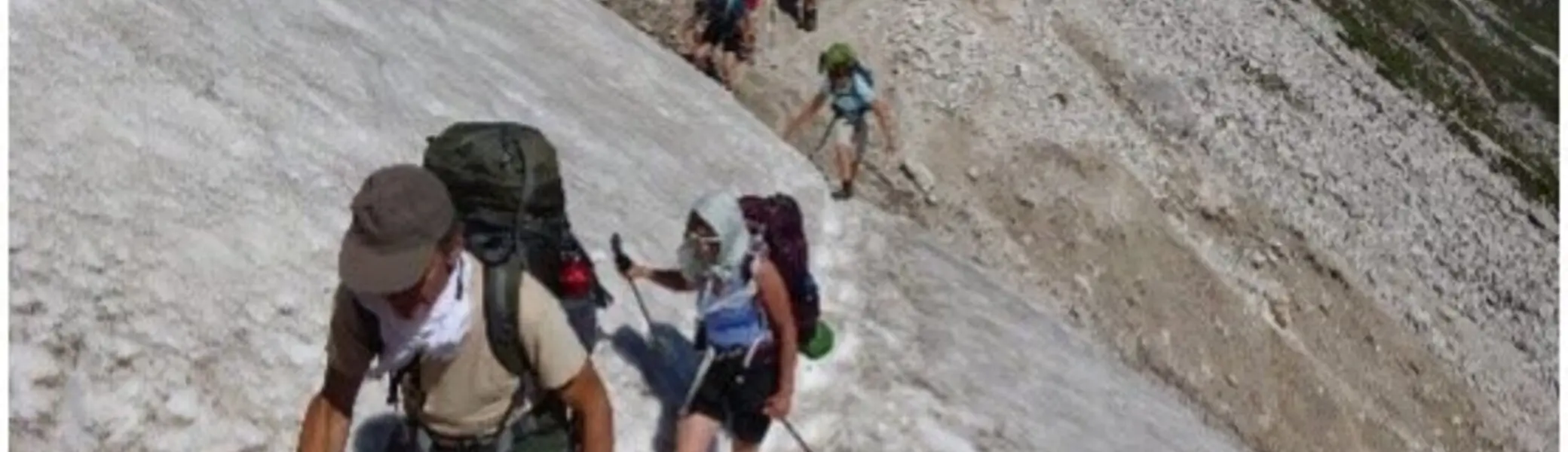 Gruppe von Wanderern quert ein Schneefeld auf einem Berghang, mit Rucksäcken ausgerüstet. | © DAV Dortmund