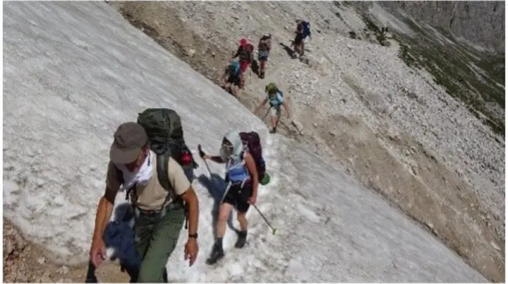 Gruppe von Wanderern quert ein Schneefeld auf einem Berghang, mit Rucksäcken ausgerüstet. | © DAV Dortmund
