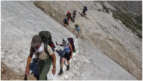 Gruppe von Wanderern quert ein Schneefeld auf einem Berghang, mit Rucksäcken ausgerüstet. | © DAV Dortmund