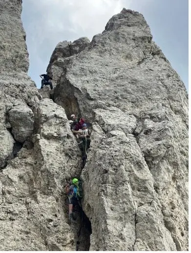 Vier Personen klettern an einem steilen Felsspalt zwischen zwei hohen Felswänden. | © DAV Dortmund