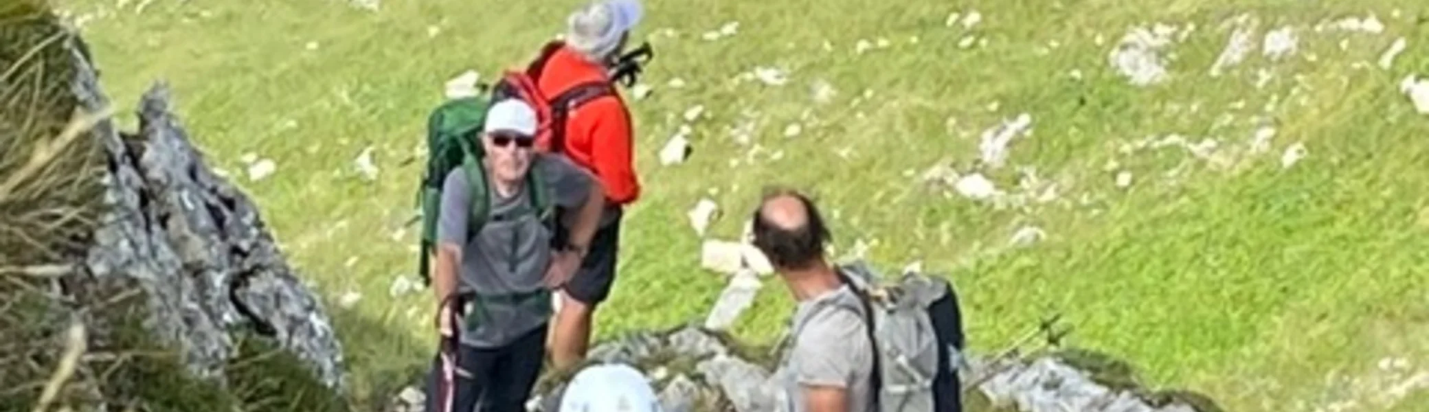 Fünf Wanderer stehen und sitzen im steilen, grünen Gelände. | © KD Schüler 