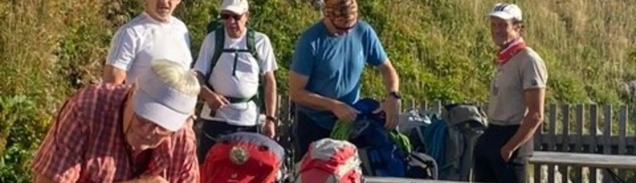 Eine Gruppe Wanderer steht mit Rucksäcken an Bänken vor einer Hütte. | © KD Schüler 