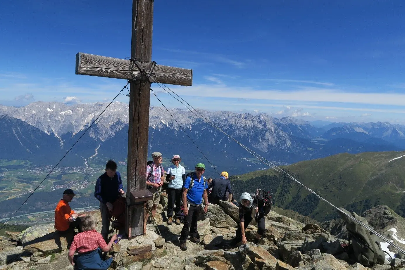 Eine größere Wandergruppe steht am Gipfelkreuz mit Blick auf das umliegende Alpenpanorama. | © DAV Dortmund