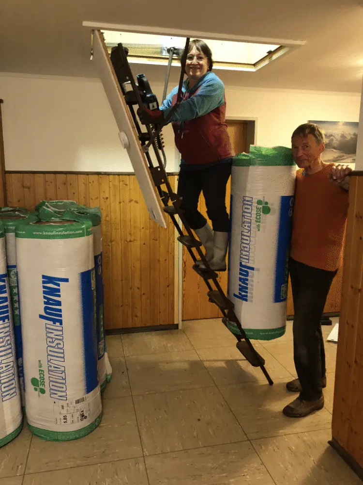 Zwei Personen reichen große Rollen Dämmmaterial durch eine geöffnete Dachluke. | © DAV Dortmund