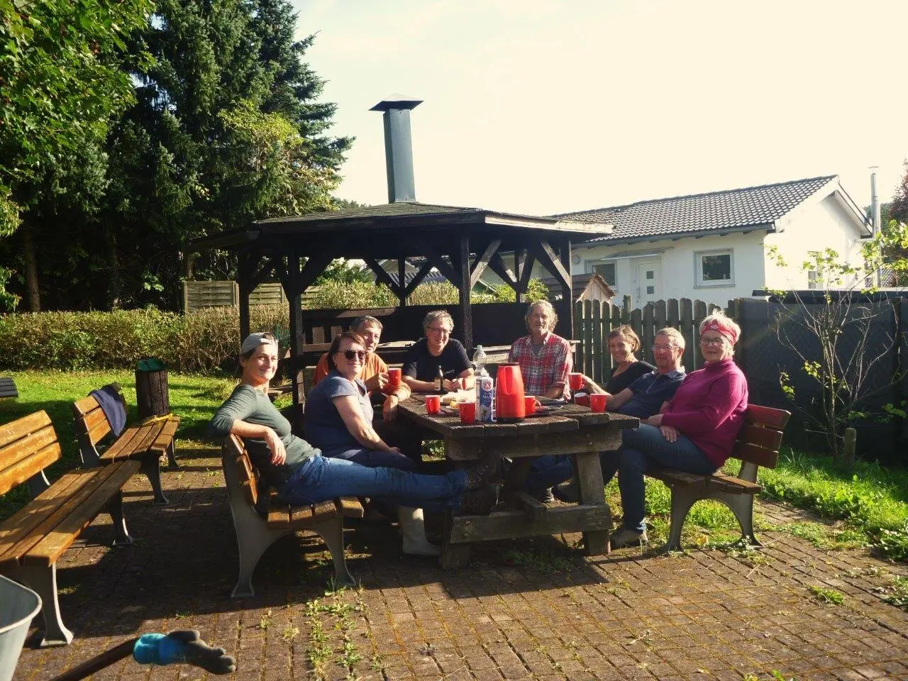 Sieben Personen sitzen gemütlich an einem Gartentisch bei Sonnenschein, Getränke auf dem Tisch. | © DAV Dortmund
