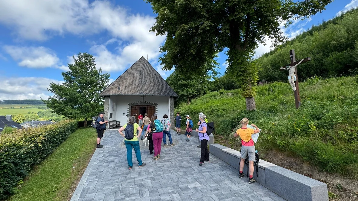 Die Wandergruppe steht vor einer kleinen Kapelle auf einer Anhöhe mit Blick ins Tal. Rechts daneben steht ein großes Holzkreuz mit Jesusfigur. | © DAV Dortmund