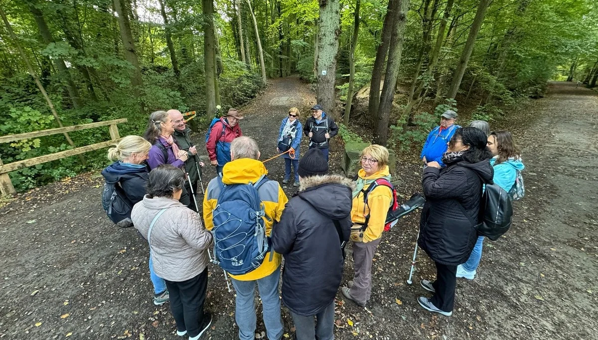 Die Gruppe bildet im Wald einen Kreis, viele tragen bunte Jacken und Rucksäcke. | © DAV Dortmund