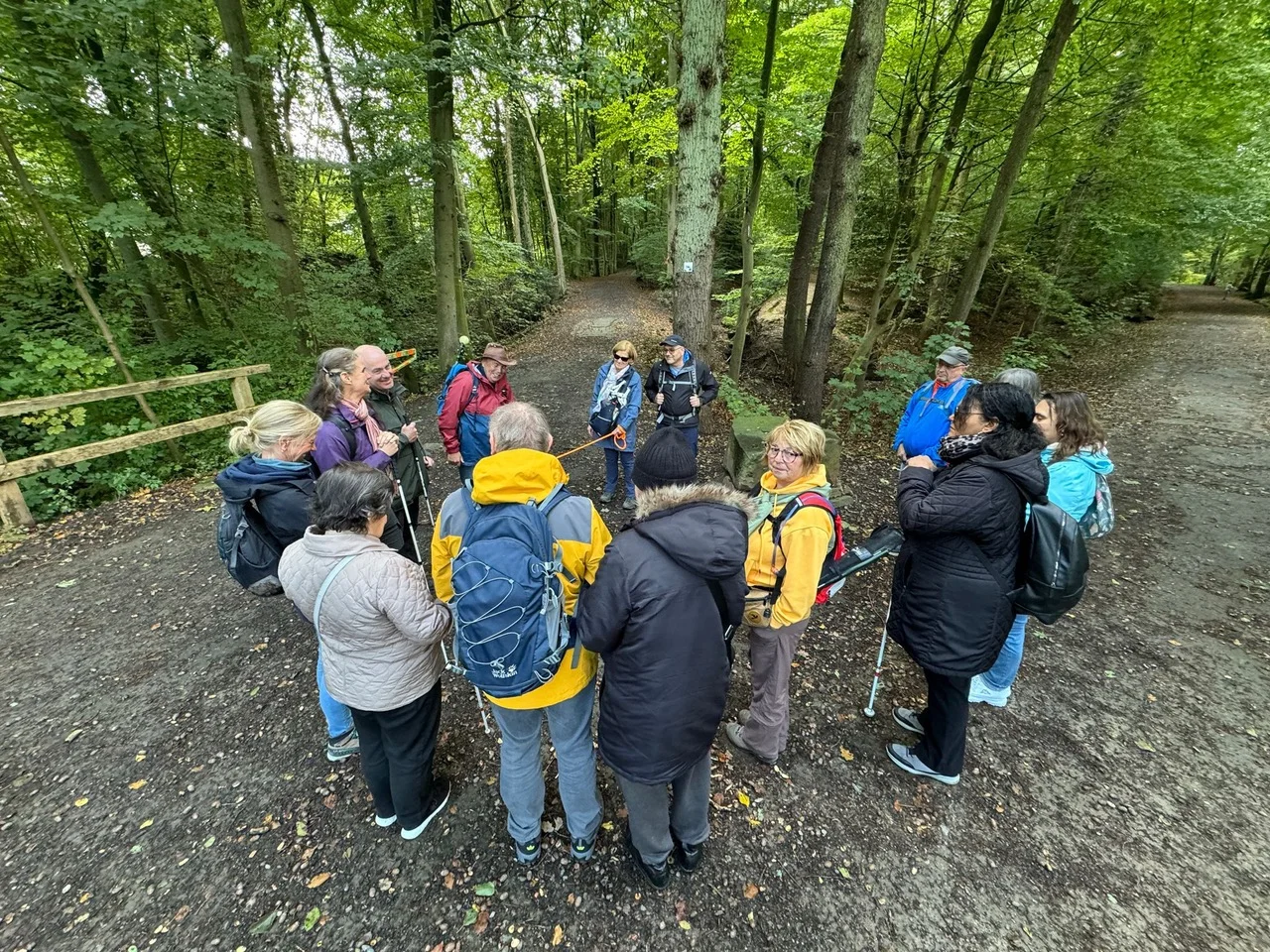 Die Gruppe bildet im Wald einen Kreis, viele tragen bunte Jacken und Rucksäcke. | © DAV Dortmund