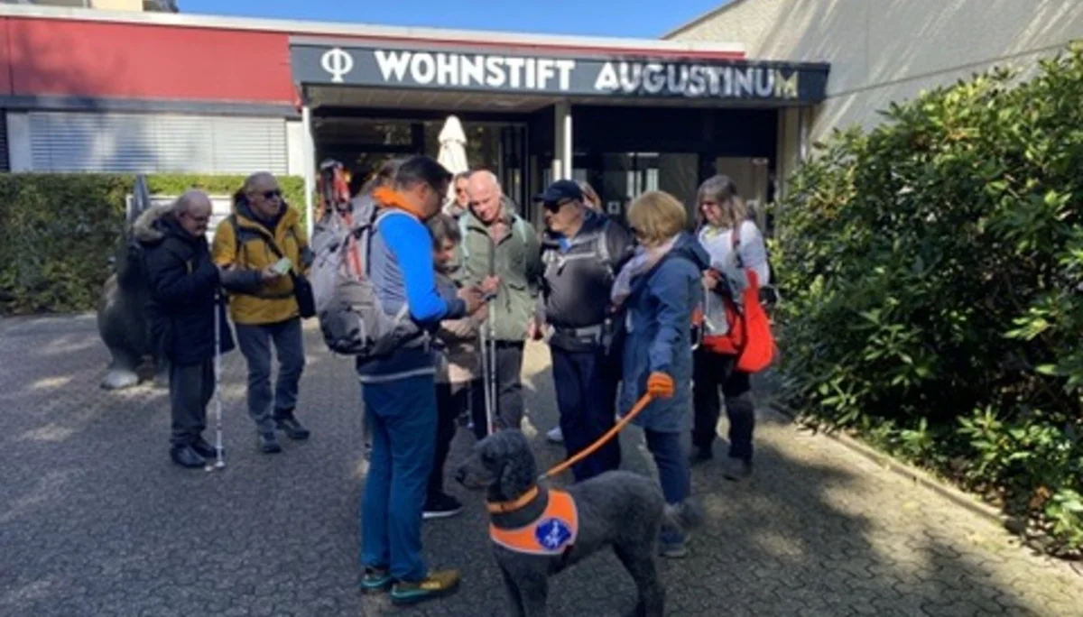 Die Wandergruppe steht vor dem Eingang des Wohnstifts Augustinum mit einem Assistenzhund. | © DAV Dortmund