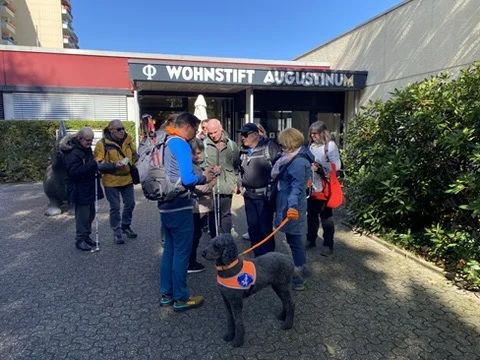 Die Wandergruppe steht vor dem Eingang des Wohnstifts Augustinum mit einem Assistenzhund. | © DAV Dortmund