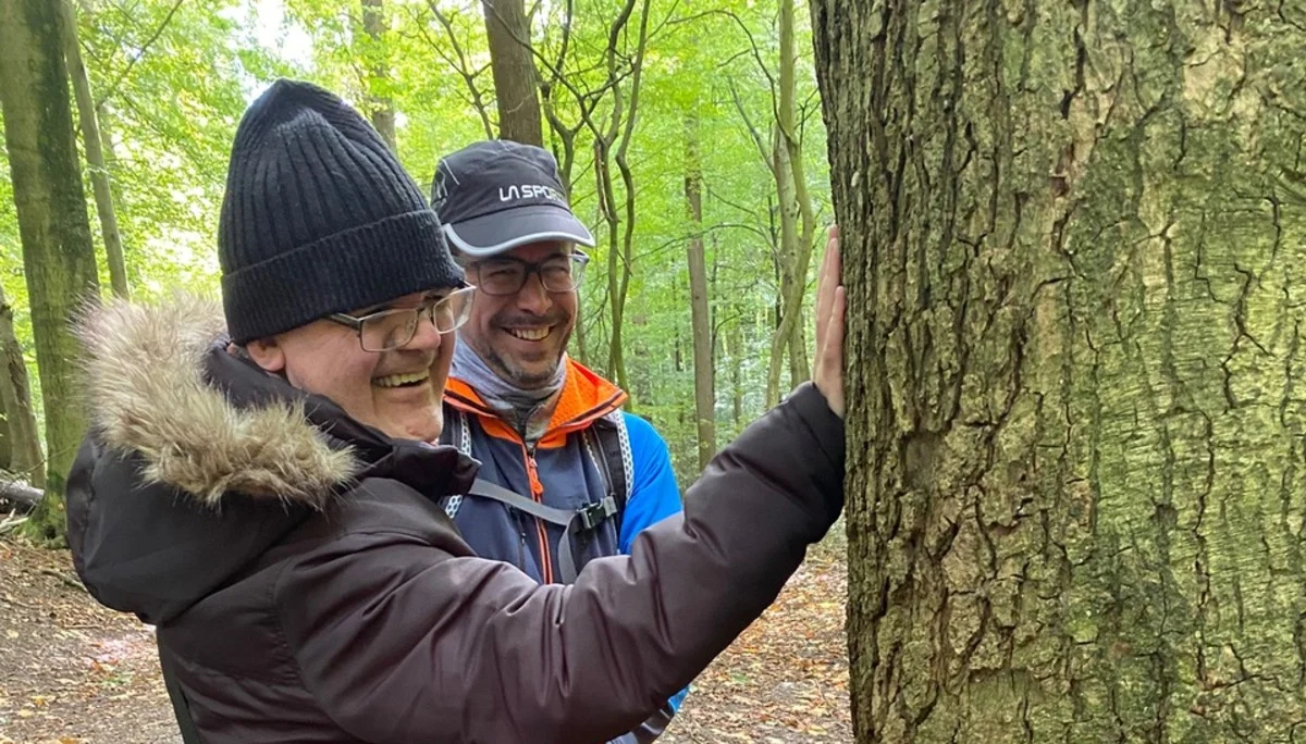 Eine blinde Frau ertastet mit Begleitung die Rinde eines Baumes im Wald. | © DAV Dortmund